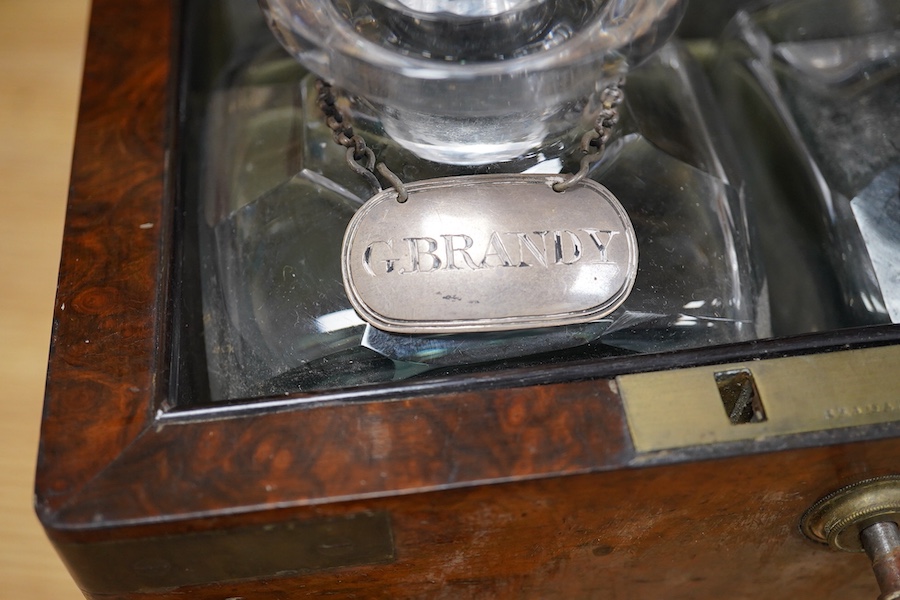 A Victorian burr walnut and brass bound four bottle decanter box, the four faceted square decanters with Victorian silver spirit labels, Bramah lock with key, 26cm high